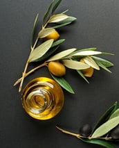 olive oil in a glass bottle with olives and olive leaves