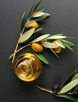 olive oil in a glass bottle with olives and olive leaves
